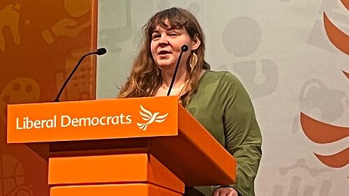 Katharine Macy standing behind a Lib Dem conference podium